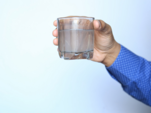 Man holding a glass of rusty water 